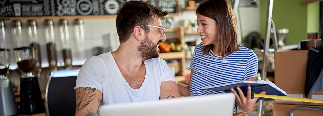 Jong stel praat en lacht terwijl ze ontbijten in het koffiehuis dat ze op het punt staan ​​te openen.